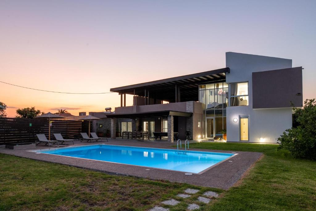 a house with a swimming pool in front of it at Marane Deluxe House in Ialyssos