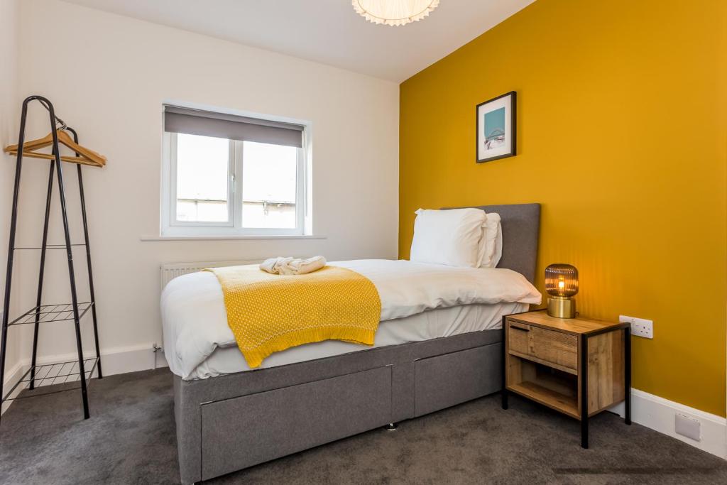 um quarto com uma cama e uma parede amarela em Luke Stays - Sea View em Hirst