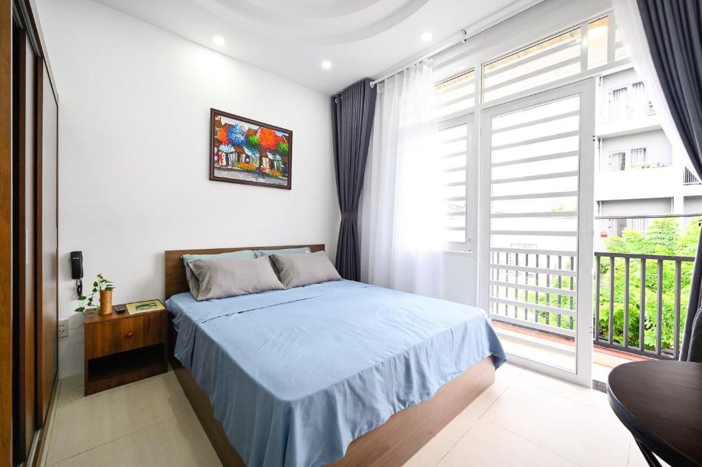 um quarto com uma cama e uma grande janela em VANAPARTMENT em Ho Chi Minh