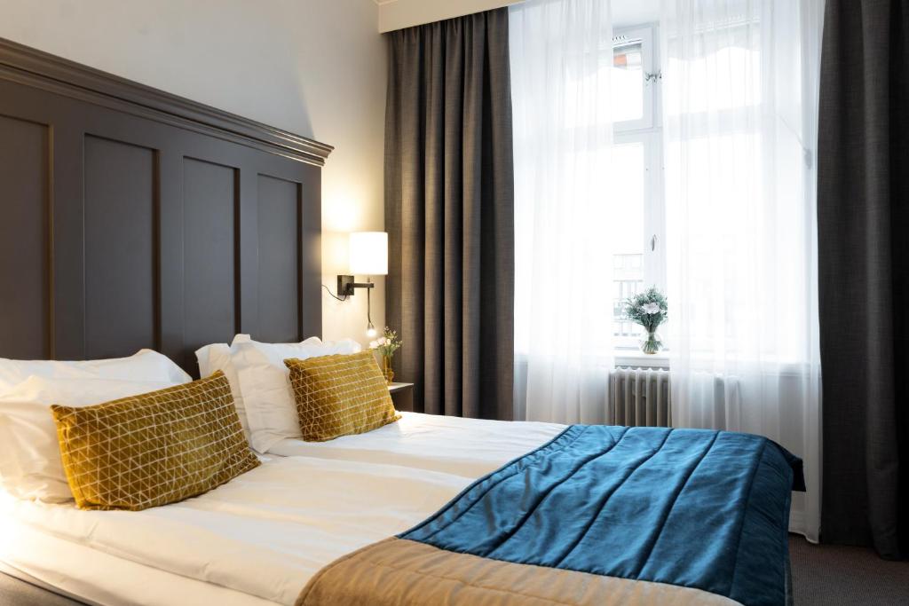 um quarto com uma cama grande com almofadas amarelas e azuis em Elite Stora Hotellet Linköping em Linköping