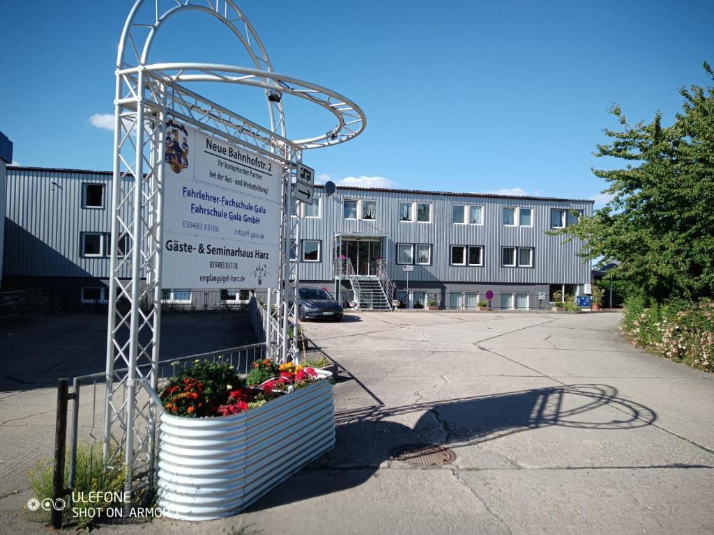 a sign in front of a building with flowers at Gäste & Seminarhaus Harz in Ballenstedt