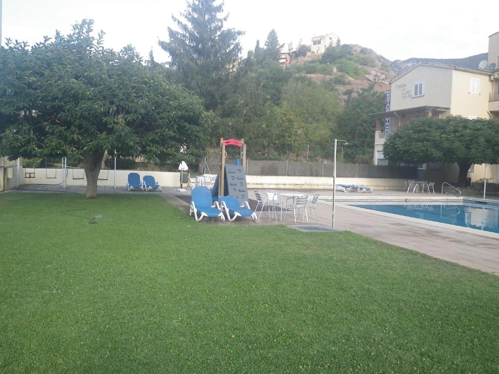 a yard with blue chairs and a swimming pool at Cal toà in Coll de Nargó