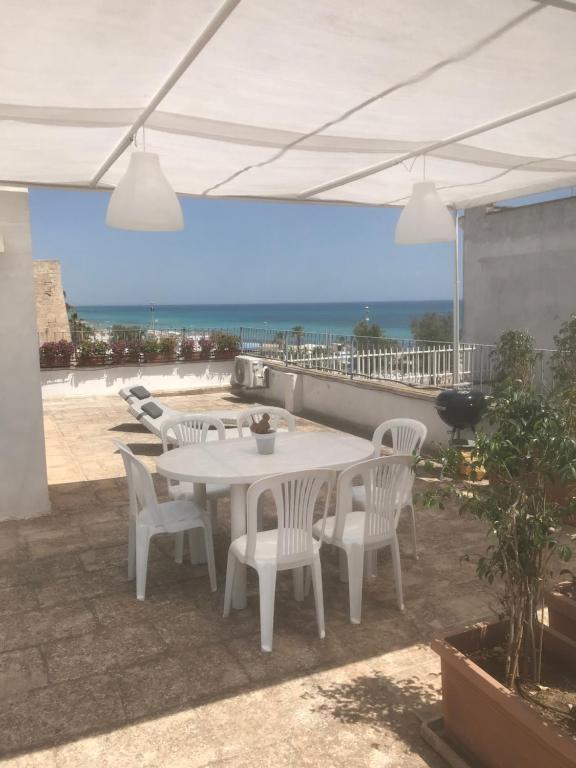 einen weißen Tisch und Stühle auf einer Terrasse mit Meerblick in der Unterkunft A 100metri dal mare difronte alla torre saracena. in Campomarino