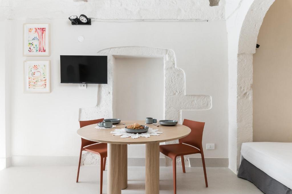 a dining room table with two chairs and a tv at Petragrigia Vacation Suite in Ostuni