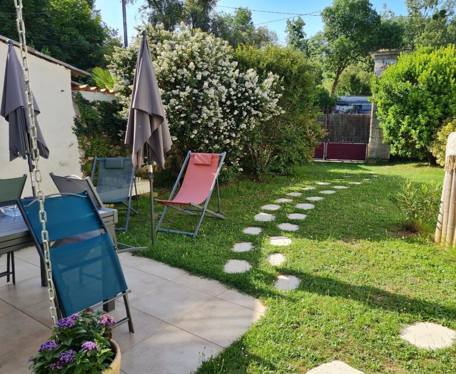 a garden with chairs and an umbrella at Maison de Campagne cosy in Pons