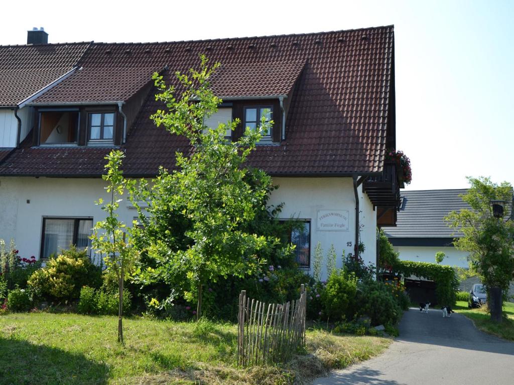 uma casa branca com uma árvore em frente em Haus Fiegle em Kressbronn am Bodensee