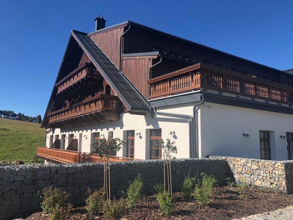 a large white house with a wooden roof at Strunzova Pila - apartmány s wellness 2,06 a 3,03 in Kvilda
