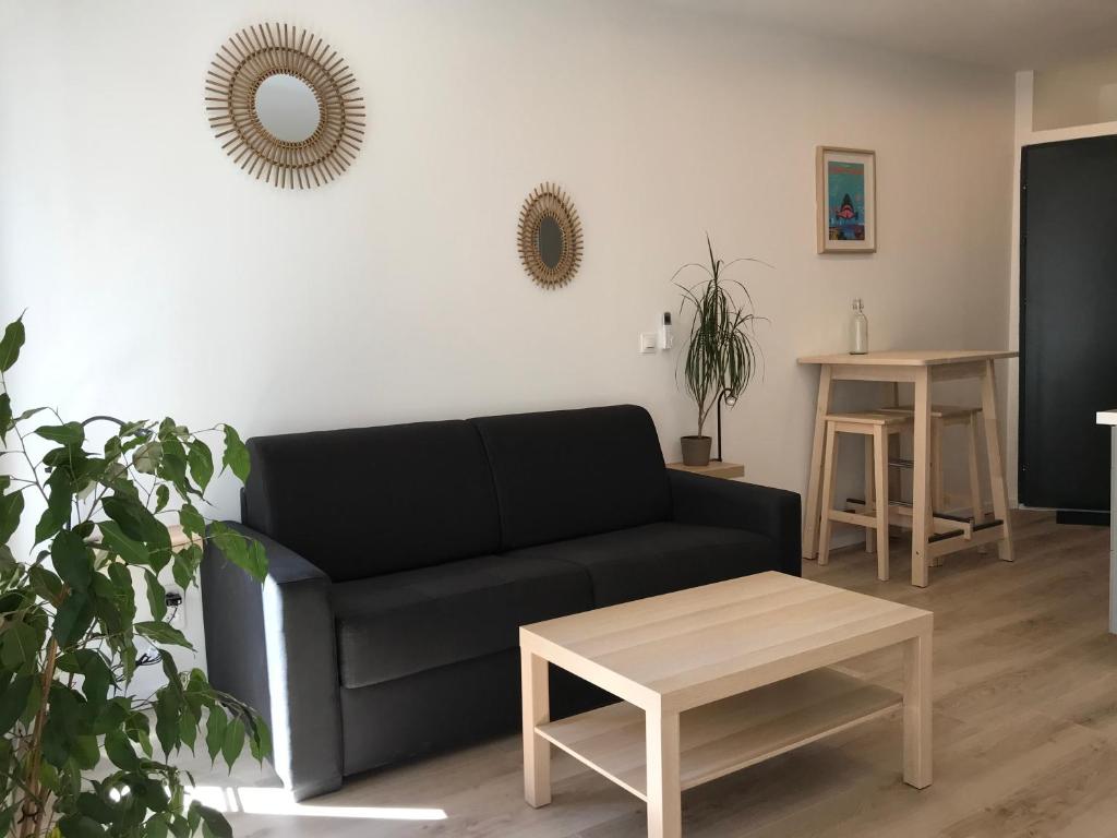 a living room with a black couch and a table at Studio Port Moderne HyperCentre Lumineux Climatisé in Toulon