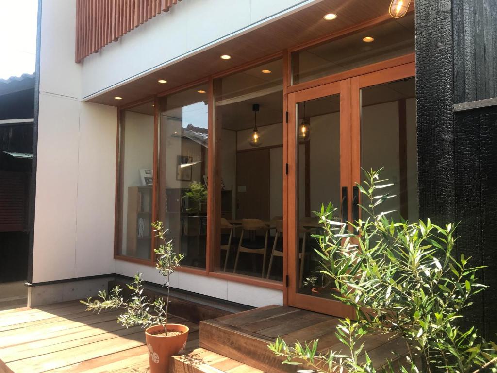 Quaint House Naoshima في ناووشيما: منزل بأبواب زجاجية ونباتات على الشرفة