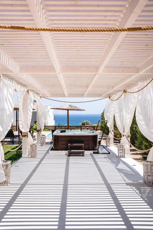 an outdoor patio with white drapes and a table at Heliophos Villa Amalthia in Kiotari
