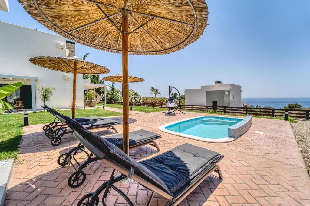 um pátio com cadeiras e guarda-sóis e uma piscina em Heliophos Villa Amalthia em Kiotari