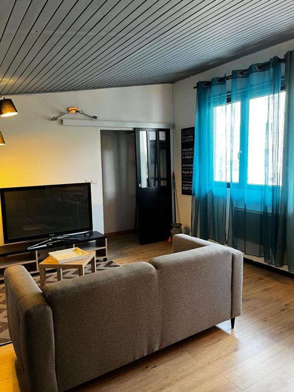 een woonkamer met een bank en een tv bij Appartement dans quartier résidentiel in Saint-Quentin