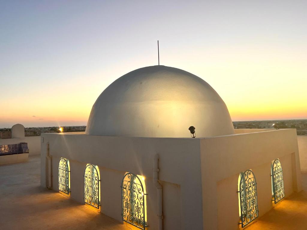 a mosque in the desert with the sunset in the background at Villa Fadila in Sidi Mansour