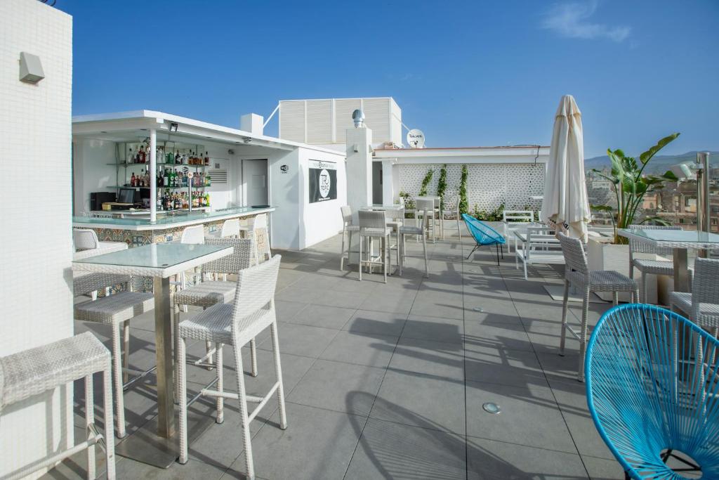 eine Terrasse mit Tischen und Stühlen sowie eine Bar in der Unterkunft Soho Boutique Bahía Málaga in Málaga