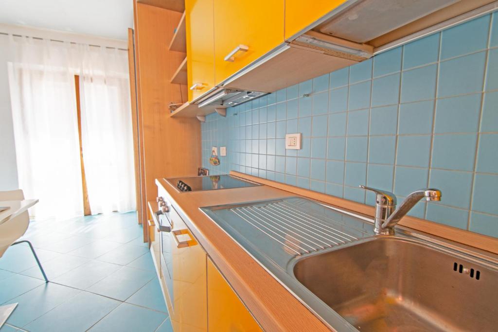 kuchnia ze zlewem ze stali nierdzewnej i niebieskimi płytkami w obiekcie Oyster Beach - Direttamente sulla Spiaggia del Forno w mieście Scaglieri