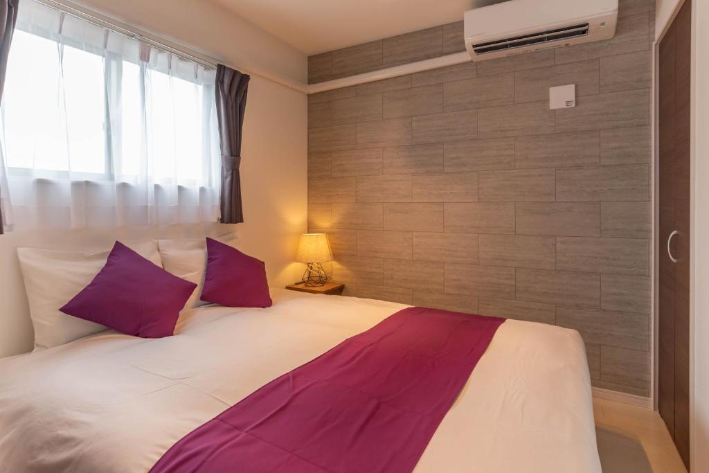1 dormitorio con 1 cama grande con almohadas moradas en FDS AIM, en Osaka