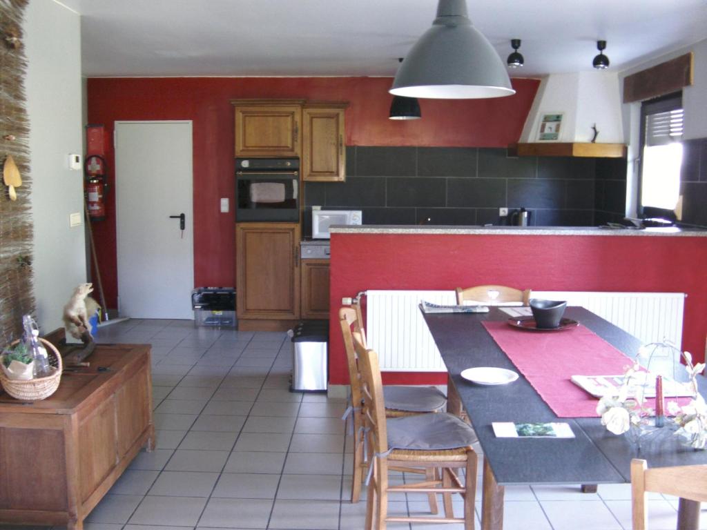 eine Küche mit einem Tisch und einer roten Wand in der Unterkunft Gîte Les Framboisiers in Neufchâteau