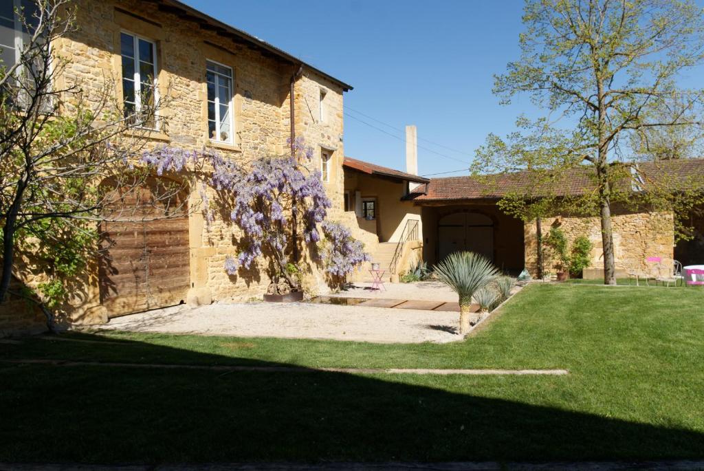 une maison avec des fleurs violettes sur son côté dans l'établissement LODGES EN PIERRES DOREES, à Saint-Germain-Nuelles