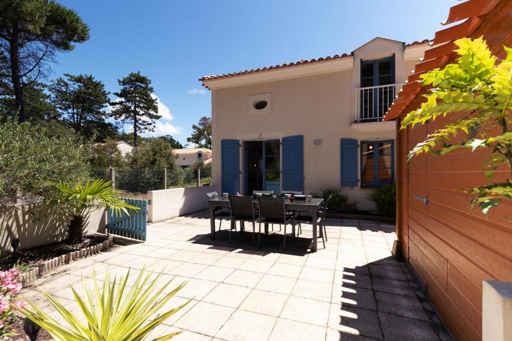 a patio with a table and chairs in front of a house at À 800m de la plage, maison pour 6 avec piscine in Plage-des-Demoiselles