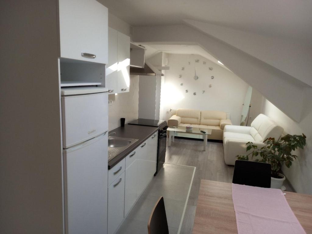 une cuisine avec des placards blancs et un salon dans l'établissement Apartmani Dubrava 2, à Zagreb