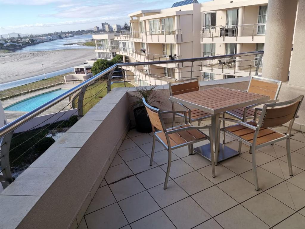 a balcony with a table and chairs and a view of the beach at Lagoon Beach Apartment 309 in Cape Town