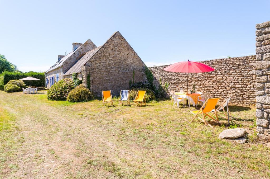 un groupe de chaises et un parasol devant un bâtiment dans l'établissement Vacances entre mer et campagne pour 8, à Plobannalec-Lesconil