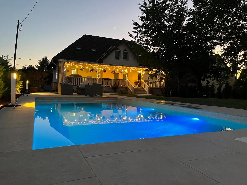 a house with a blue swimming pool in front of a house at Cherry Tree Cottage, Balatonszemes in Balatonszemes