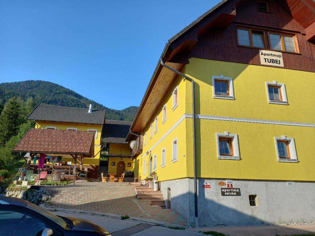 a yellow building with a brown roof at Tubej B&B family room with terrase in Bohinj