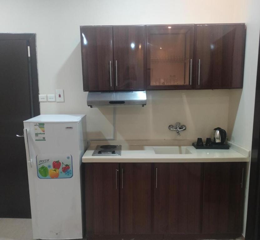 uma cozinha com armários de madeira e um frigorífico branco em شقق اطلالة اجاء المخدومة em Hail