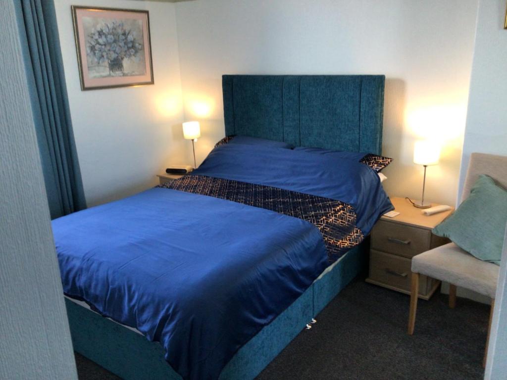 a bedroom with a blue bed and a chair at Southbourne Guest House in Llandudno