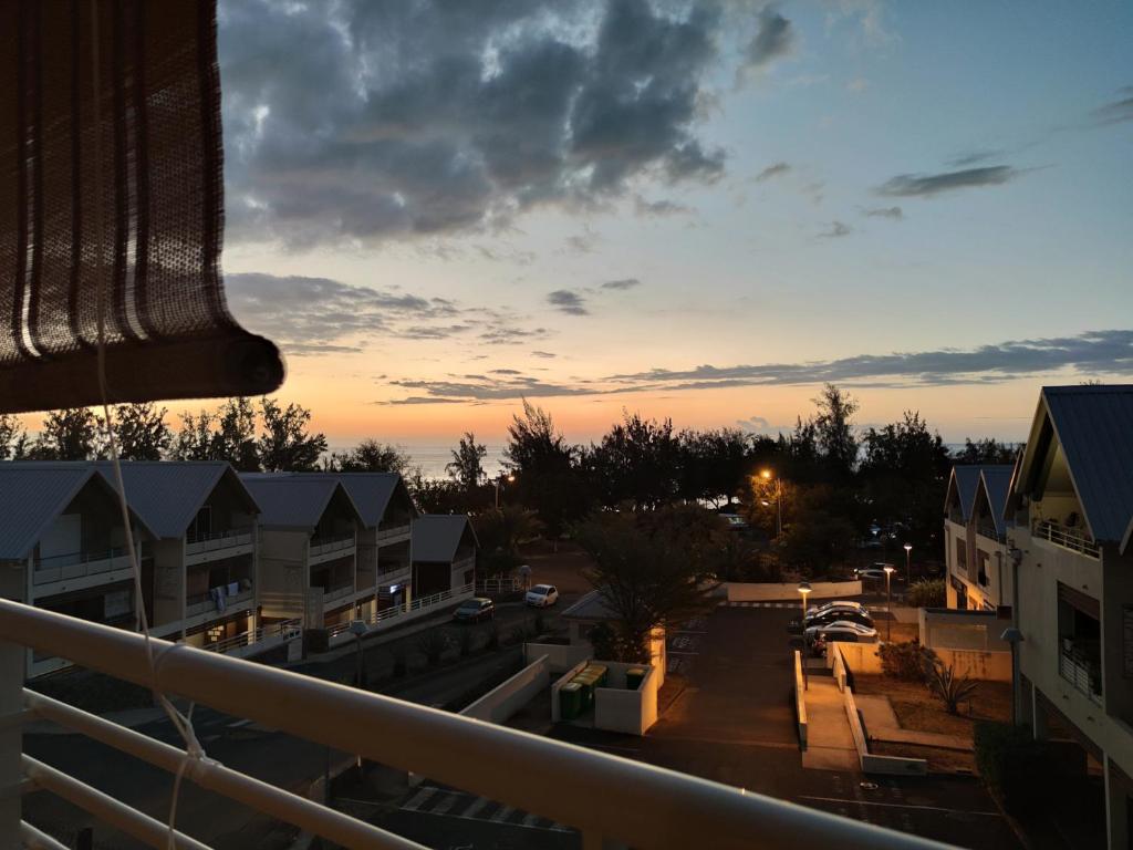 d'un balcon offrant une vue sur un parking au coucher du soleil. dans l'établissement Location saisonnière meublée F2 St Leu face océan à 1 min plage, à Saint-Leu
