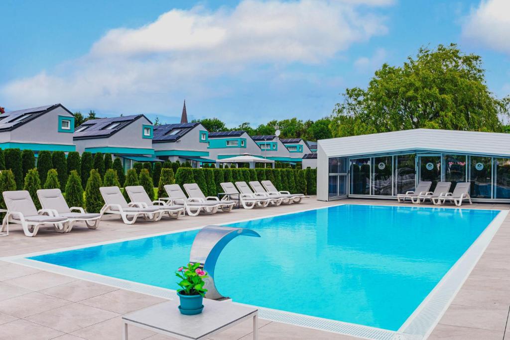 a swimming pool with lounge chairs and a house at Ośrodek Sea Star Premium in Sarbinowo