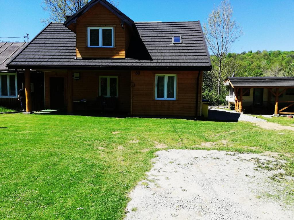 a house with a grass yard in front of it at Dom - nad Potokiem in Lutowiska