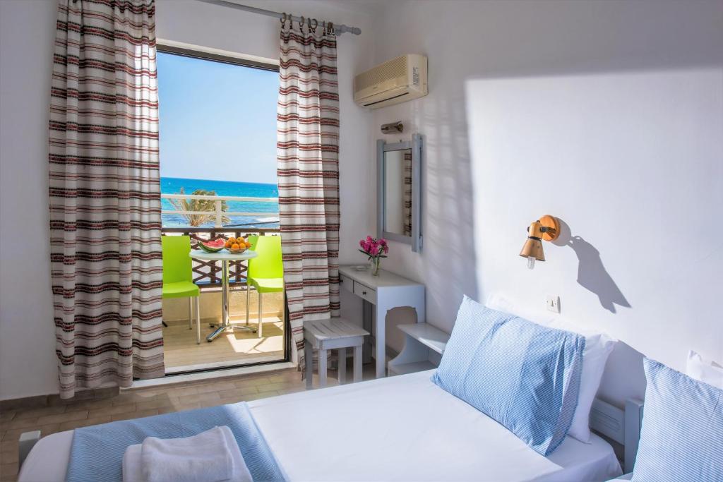 a bedroom with a bed and a view of the ocean at Smaragdine Beach Hotel in Stalís