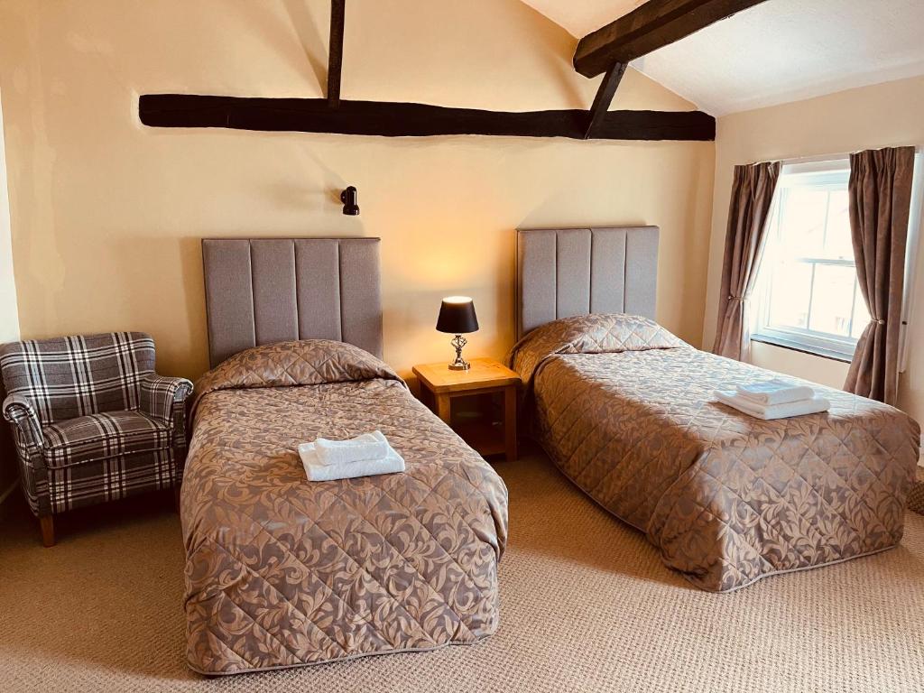 a hotel room with two beds and a chair at Cain Valley Hotel in Llanfyllin