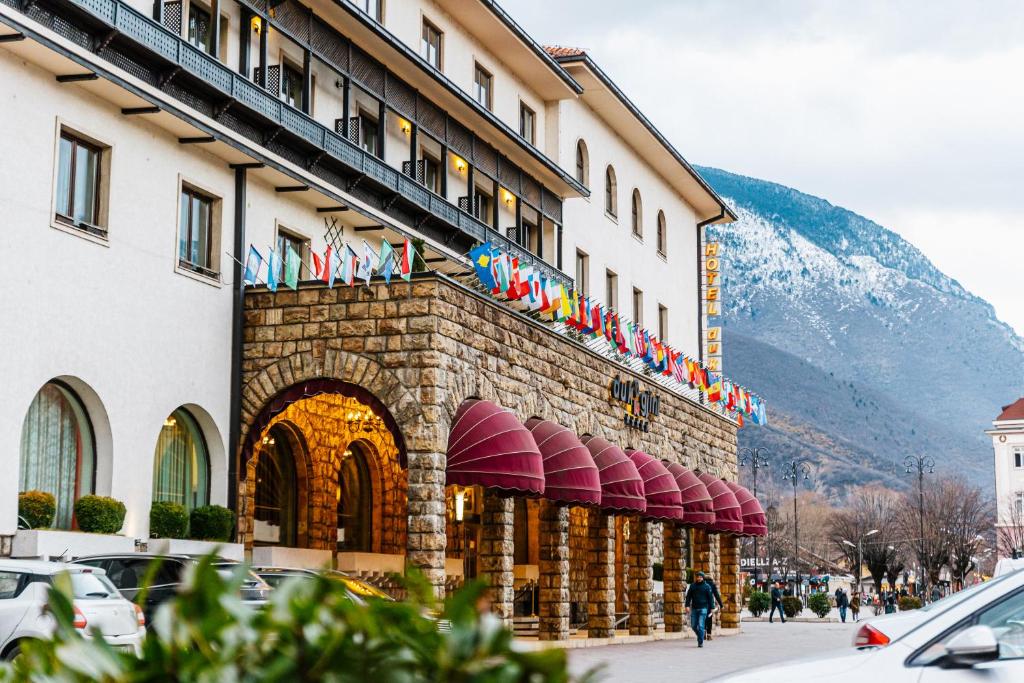 un hotel con un montón de banderas en un edificio en Hotel Dukagjini, en Peje