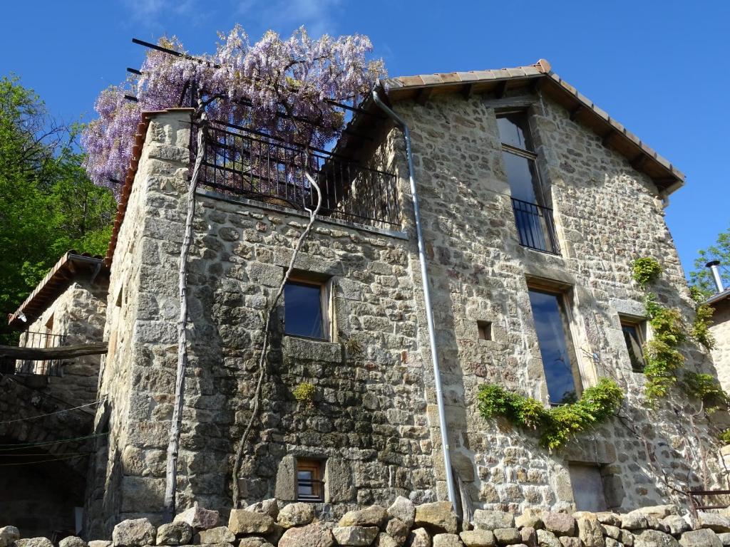 un bâtiment dont les glycérines poussent sur son côté dans l'établissement Gîte de Chapelèche Les Glycines, à Gluiras