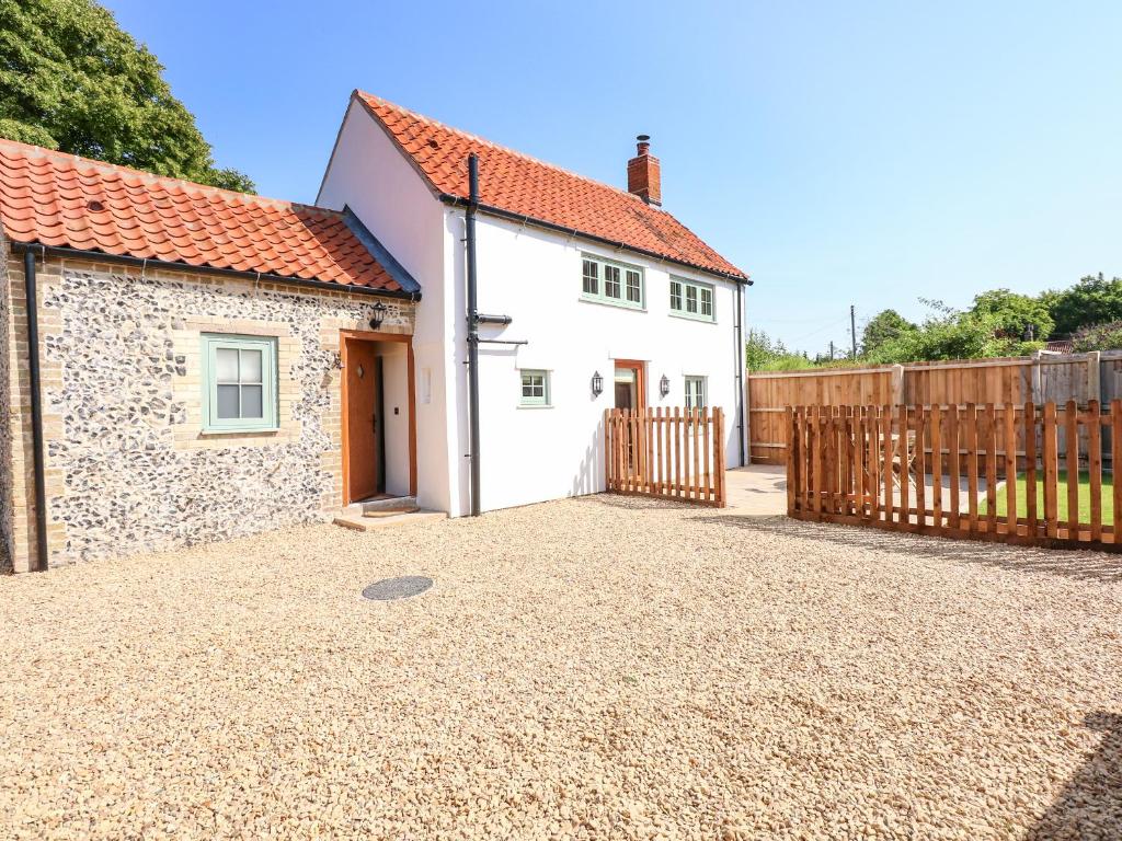 a white house with a fence and a driveway at Postbox Cottage in Thetford