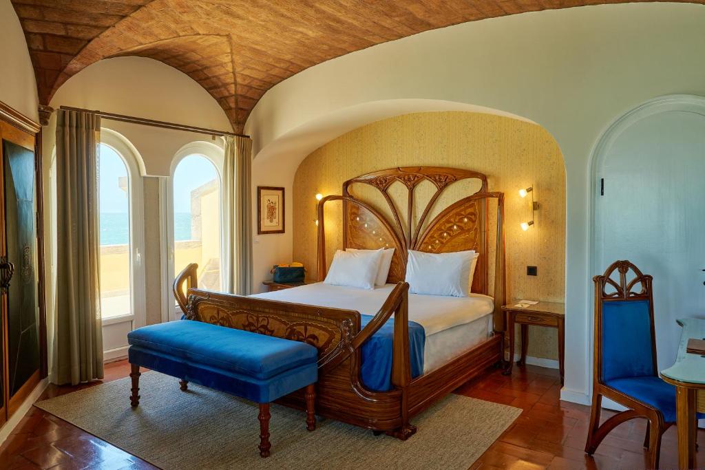 a bedroom with a large bed and a large window at Hotel Fortaleza do Guincho Relais & Châteaux in Cascais