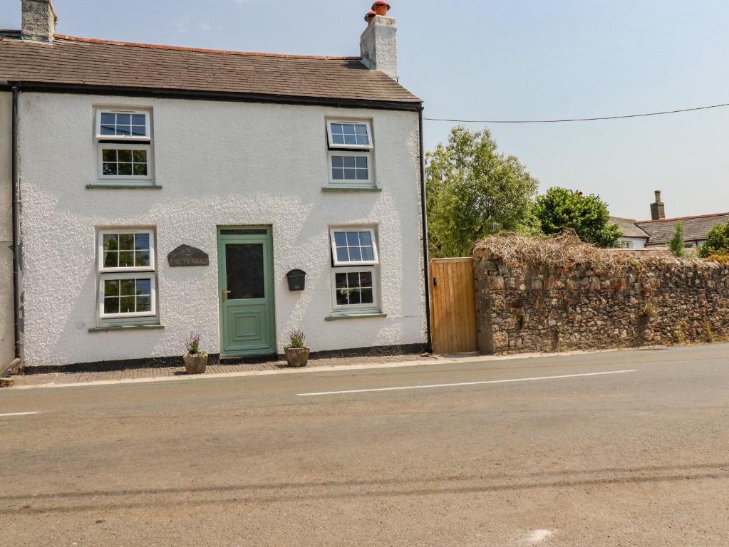 a white house with a green door on a street at Trevalba Cottage in Gunnislake