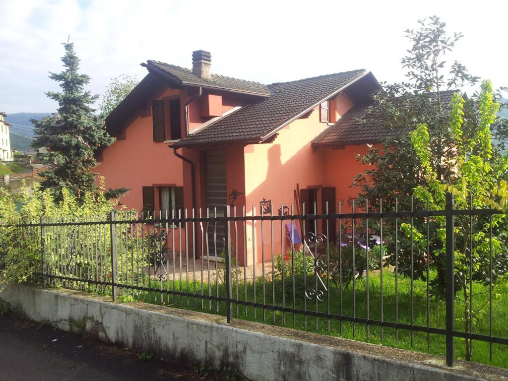 ein rosa Haus mit einem schwarzen Zaun in der Unterkunft I Tre Ciliegi Apartment in SantʼOmobono Imagna
