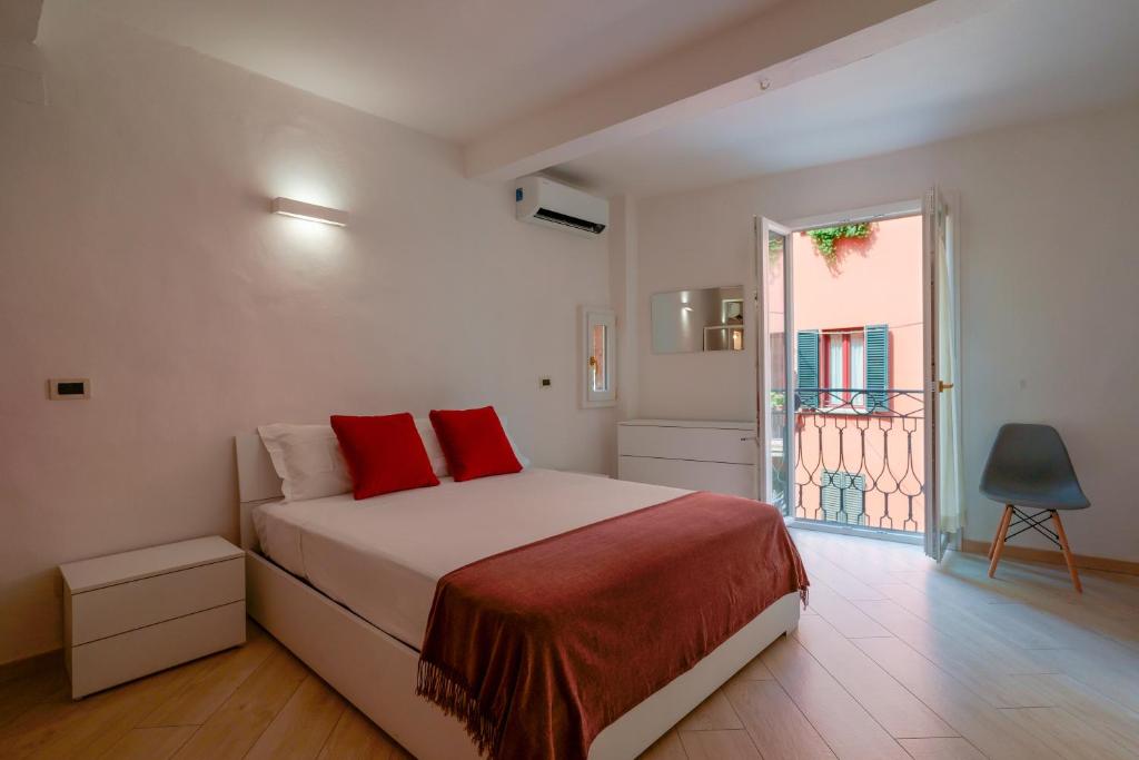 una camera da letto con un letto con cuscini rossi e una finestra di A un passo da Lucio a Bologna