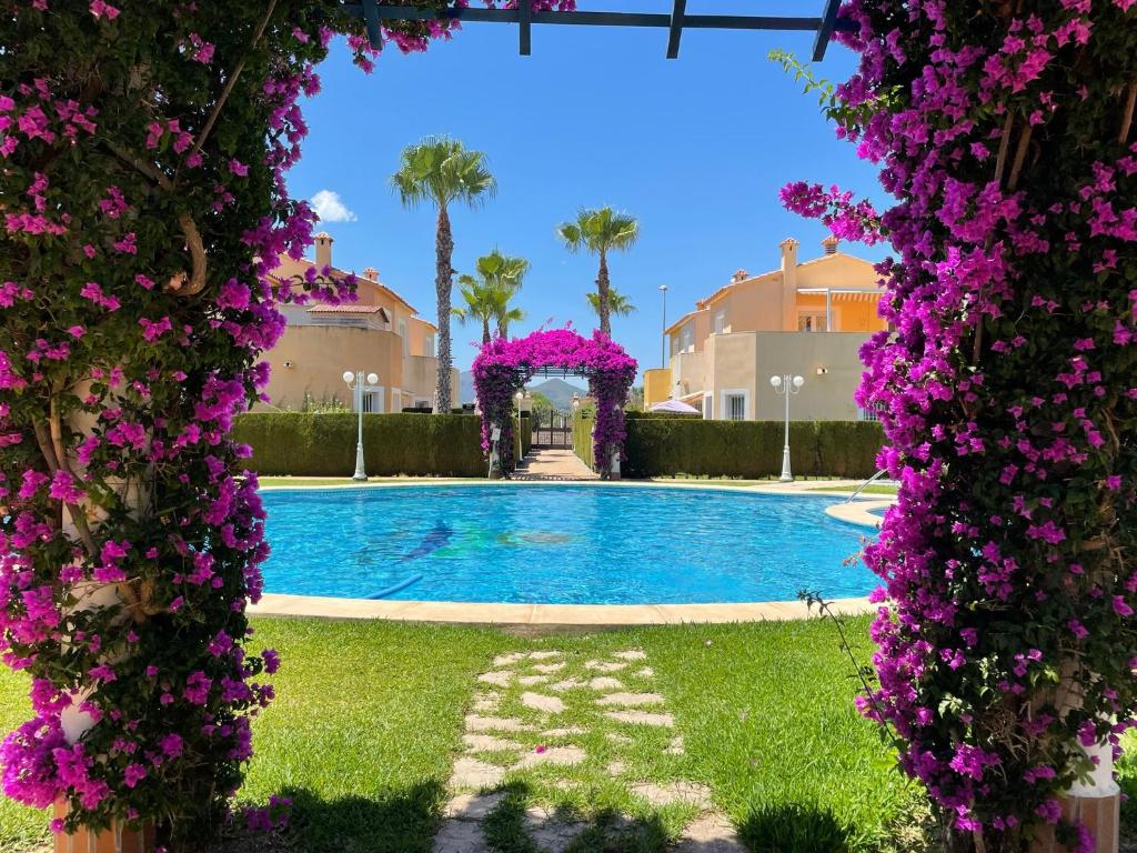 un jardín con piscina con flores púrpuras en Villa en Oliva Nova - Playa & Piscina & Golf, en Oliva