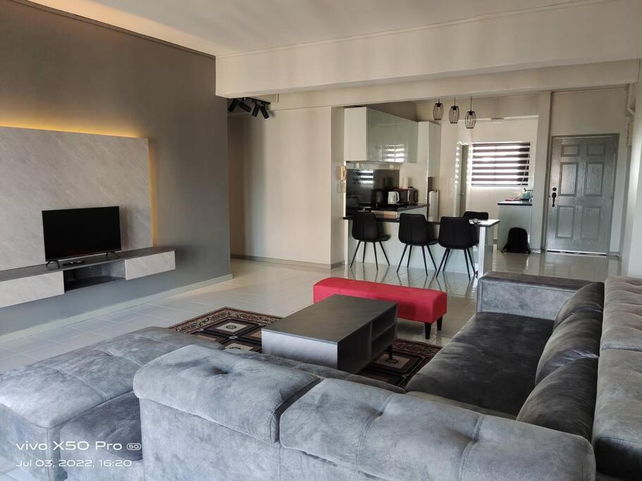 a living room with a gray couch and a table at NurIzz Condostay Homestay Pantai Puteri Melaka in Kampong Bukit Darat