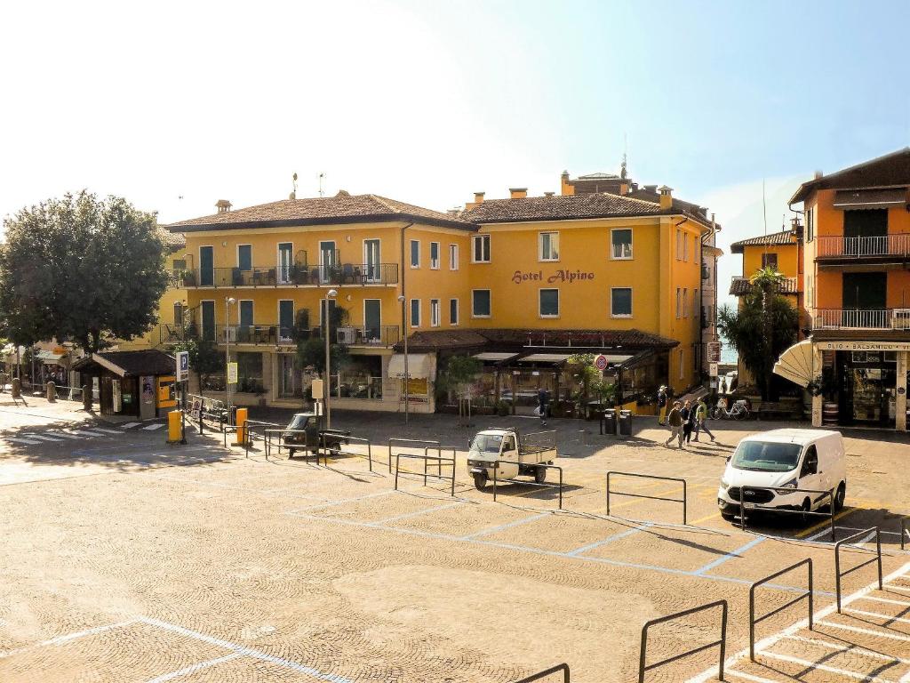 dos coches estacionados en un estacionamiento frente a los edificios en Hotel Alpino, en Malcesine
