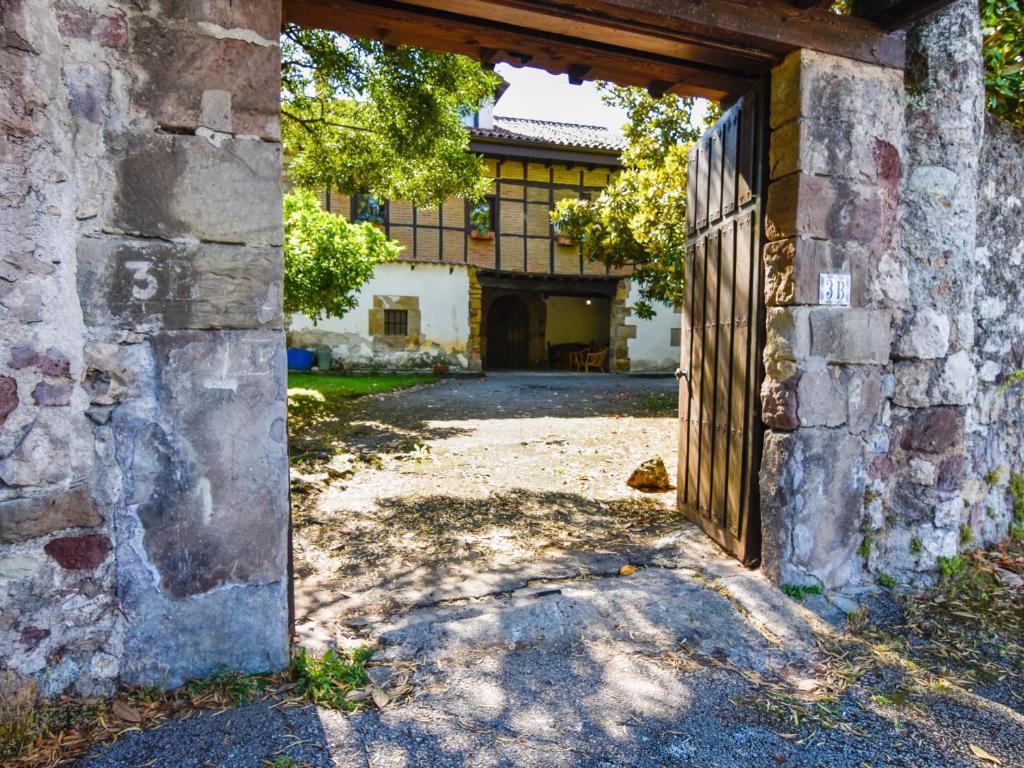uma entrada para um antigo edifício de pedra com uma porta aberta em Casona con gran jardín em Camargo