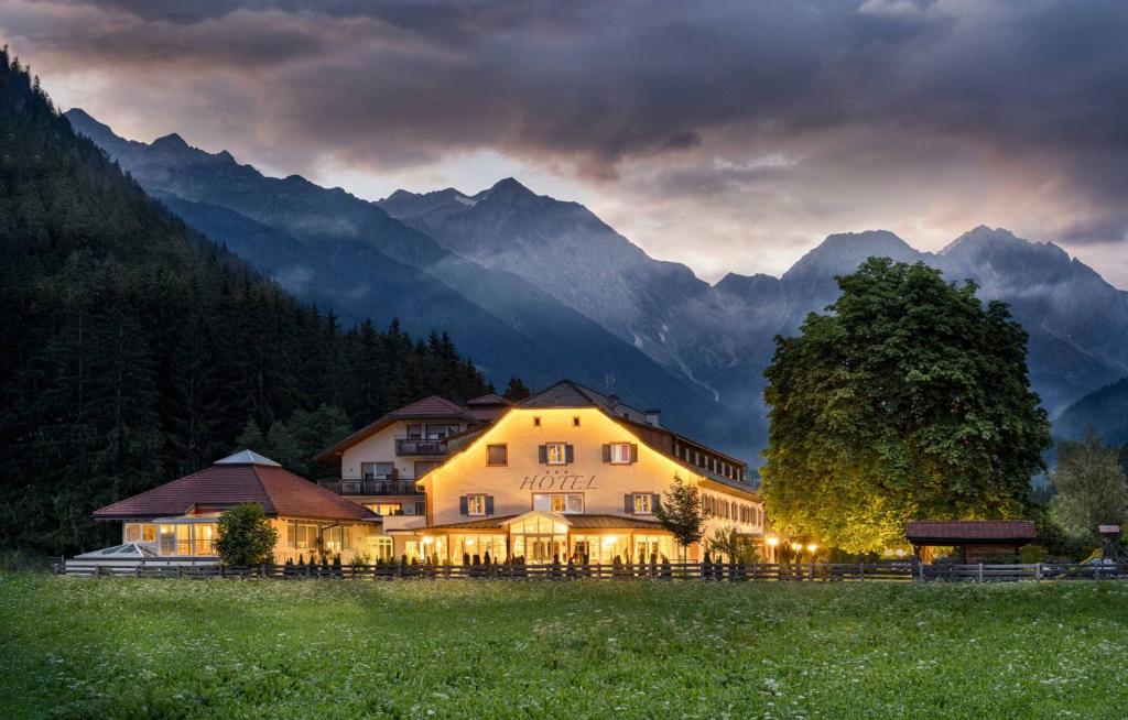 a large building in a field with mountains in the background at Hotel Bad Salomonsbrunn in Anterselva di Mezzo