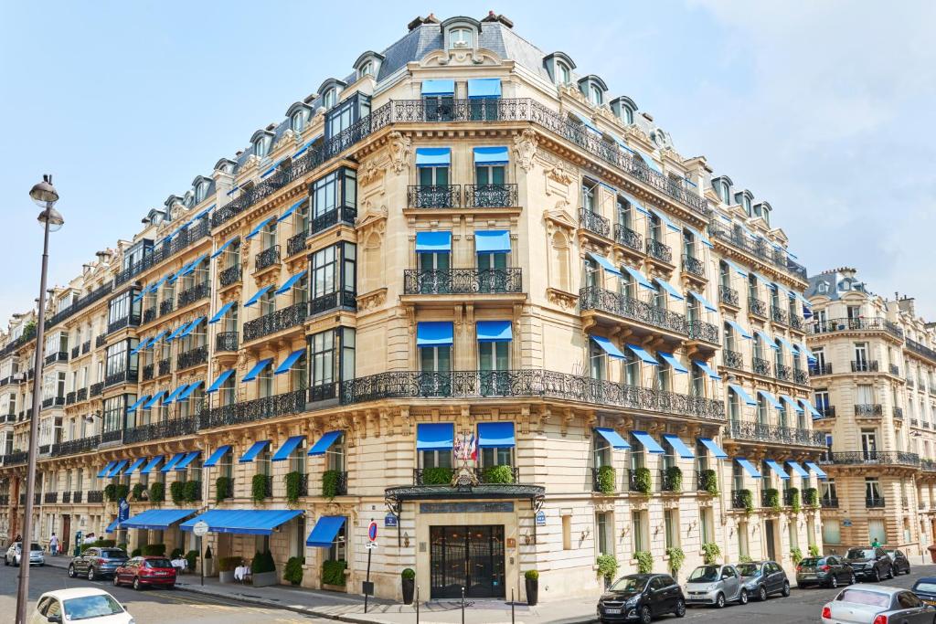 un grand bâtiment jaune avec des balcons bleus dans l'établissement La Tremoille Paris, à Paris