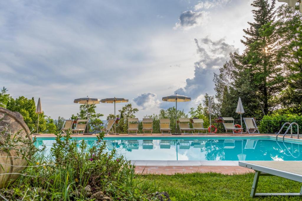 a swimming pool with chairs and umbrellas at Podere Mezzastrada in Fiano