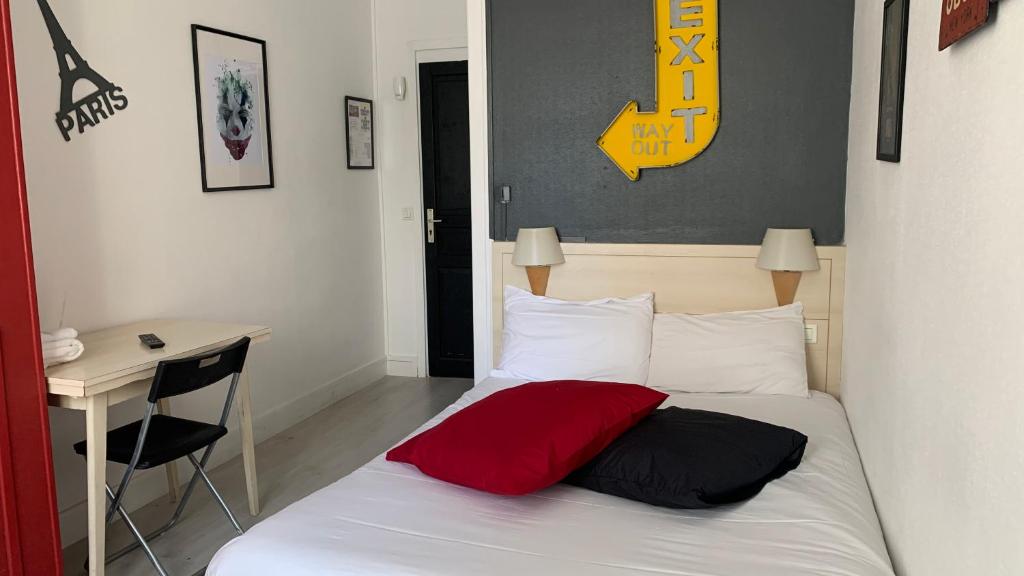 a bedroom with a bed with a red pillow and a desk at Hotel centre Rouen in Rouen